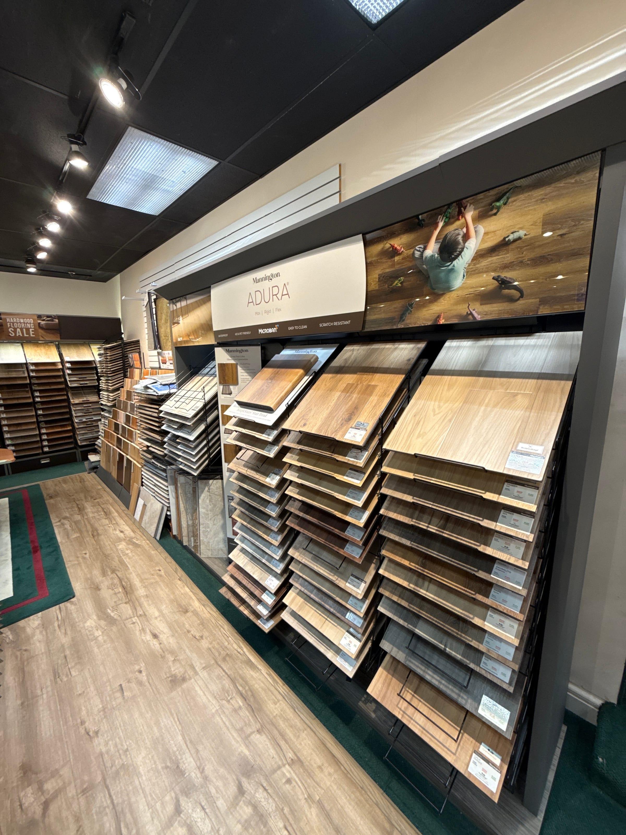 A showroom display wall of wood-look flooring samples fanned out by color and species at Carpet & Vacuum Expo.