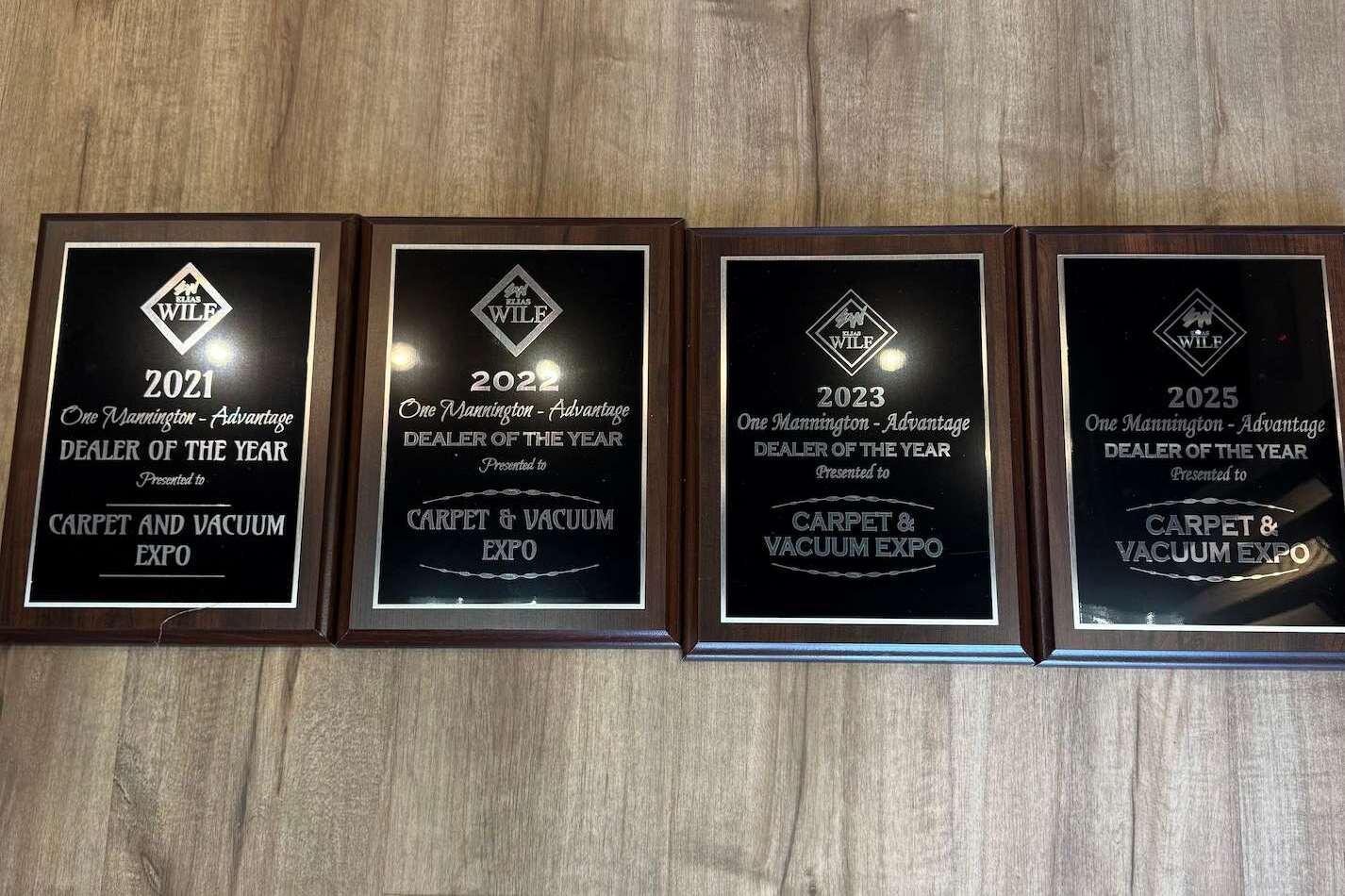 The four Mannington Dealer of the Year plaques awarded to Carpet & Vacuum Expo in 2021, 2022, 2023, and 2025.