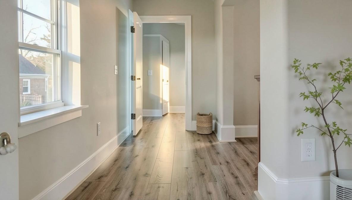 Wide-plank oak-look laminate flooring in a bright upstairs hallway with white trim and natural light.
