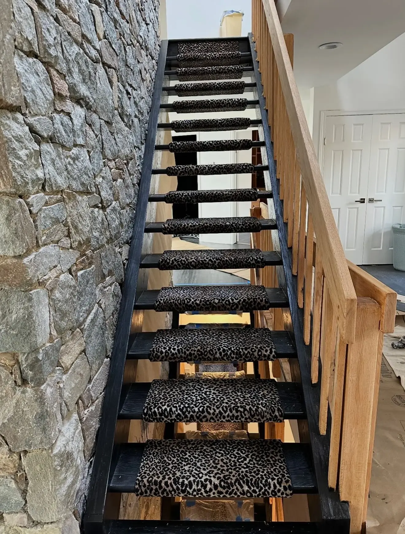 Animal-pattern runner fitted to open stairs beside a stone wall