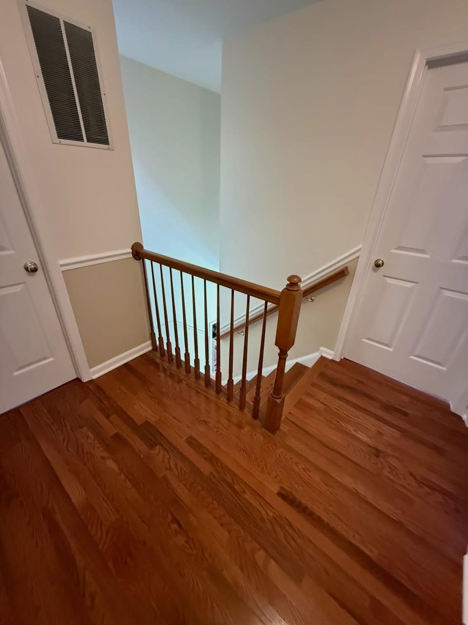 Hardwood flooring in the upstairs hallway beside the stair railing