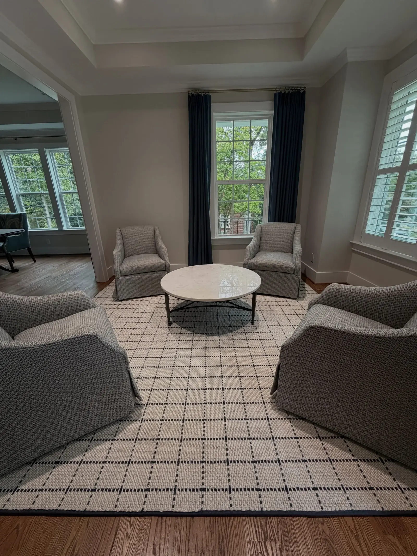 Light plaid area rug beneath chairs and a round table in a sitting room