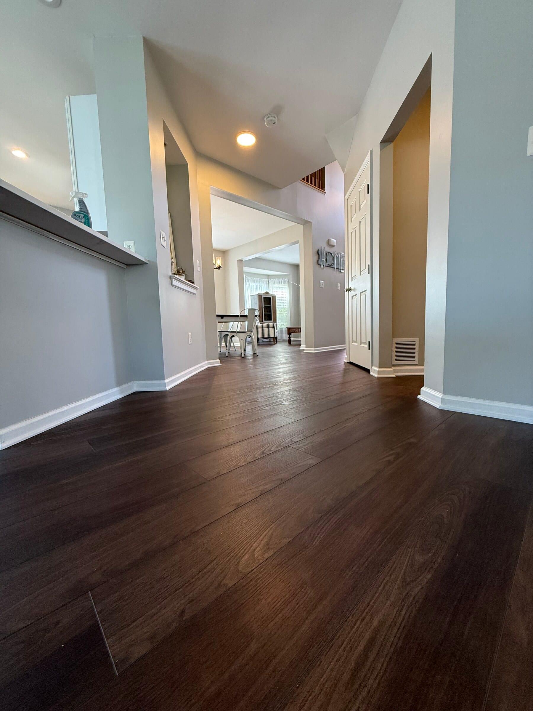 Dark flooring connecting the entry and adjoining rooms