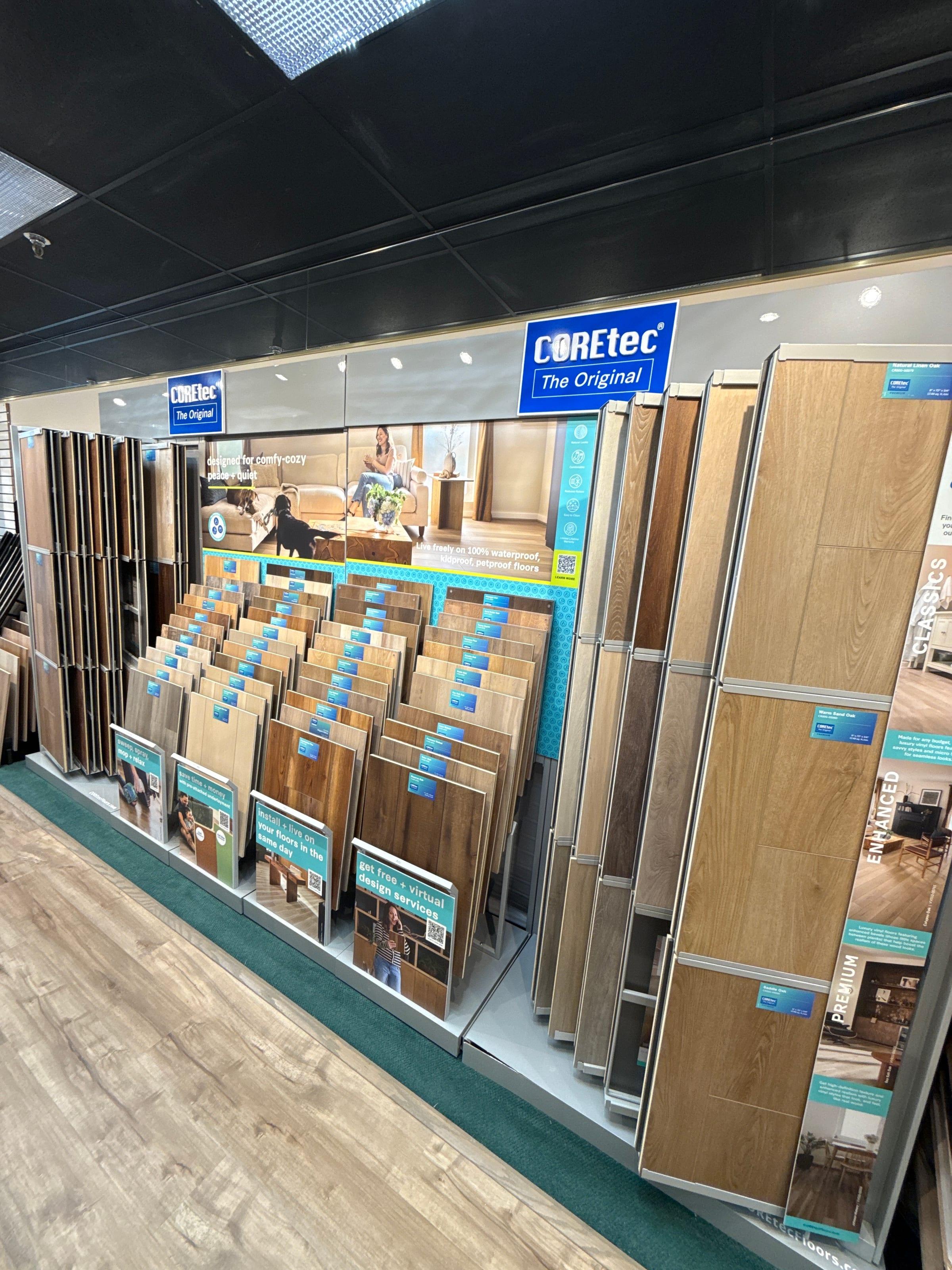 Wood-look plank samples on a display wall at the Carpet & Vacuum Expo showroom.