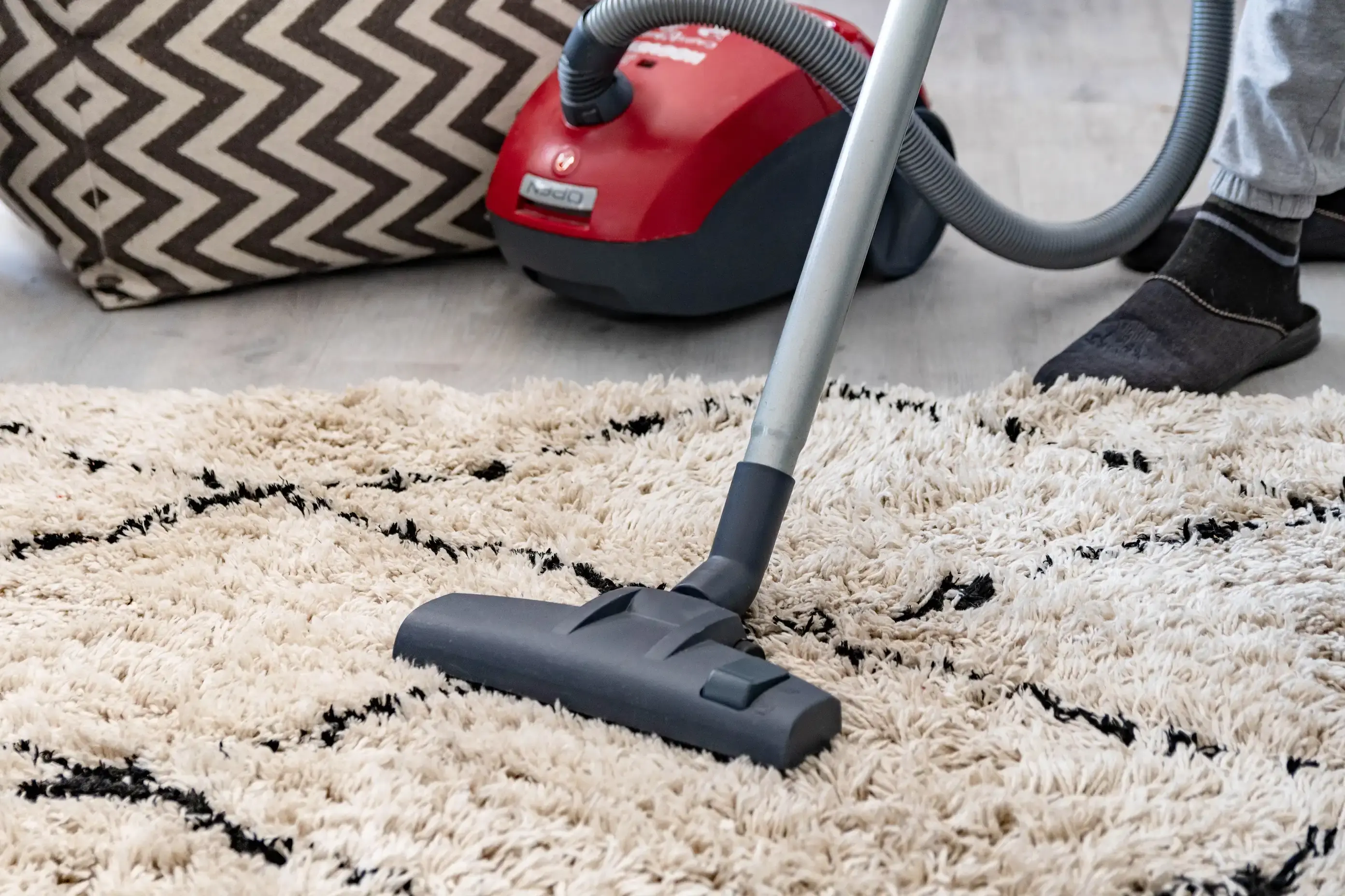 Miele Classic C1 canister vacuum cleaning a patterned wool rug at home.