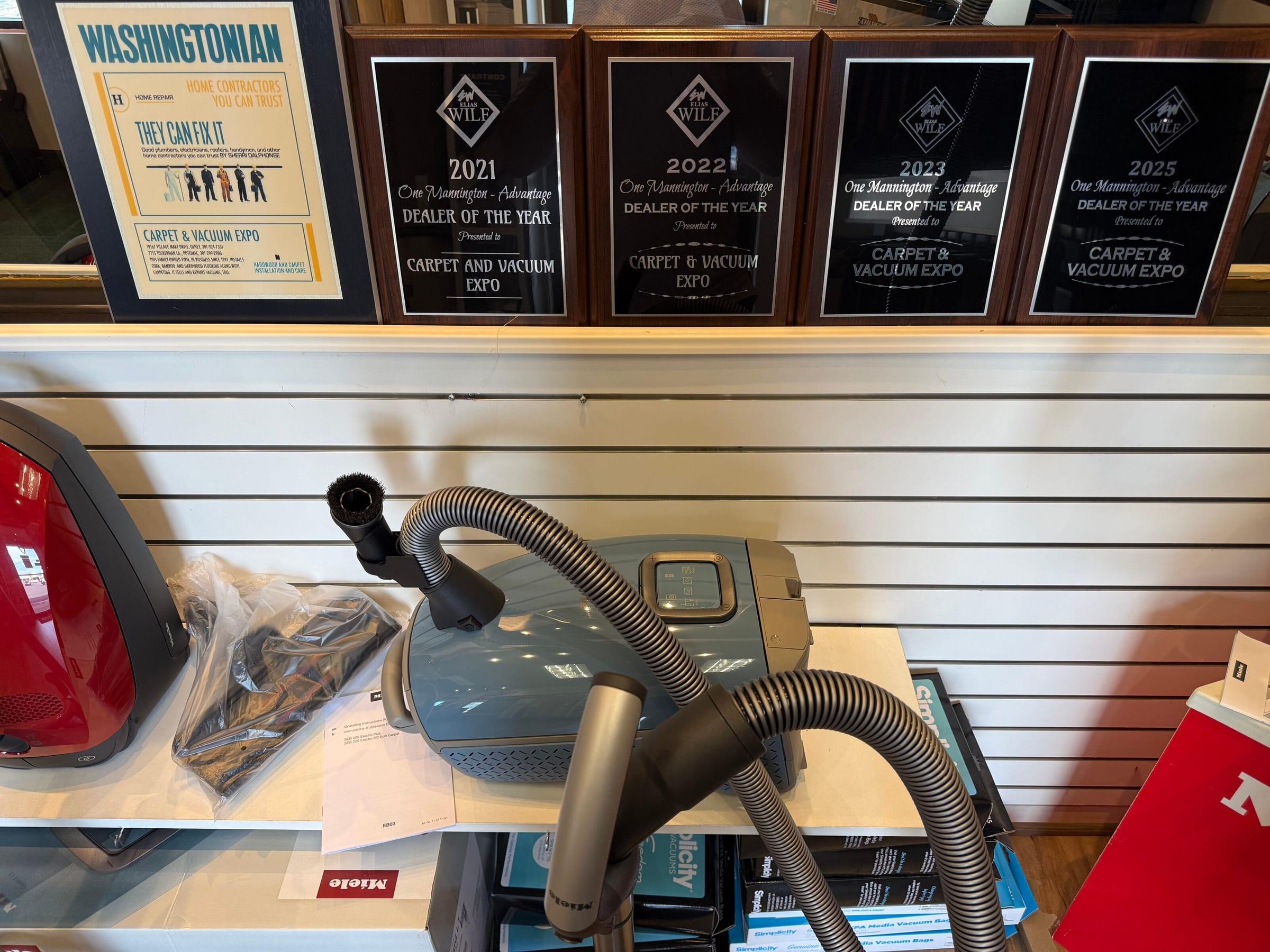 Miele canister vacuum on display beneath the Mannington Dealer of the Year awards at the Olney showroom.