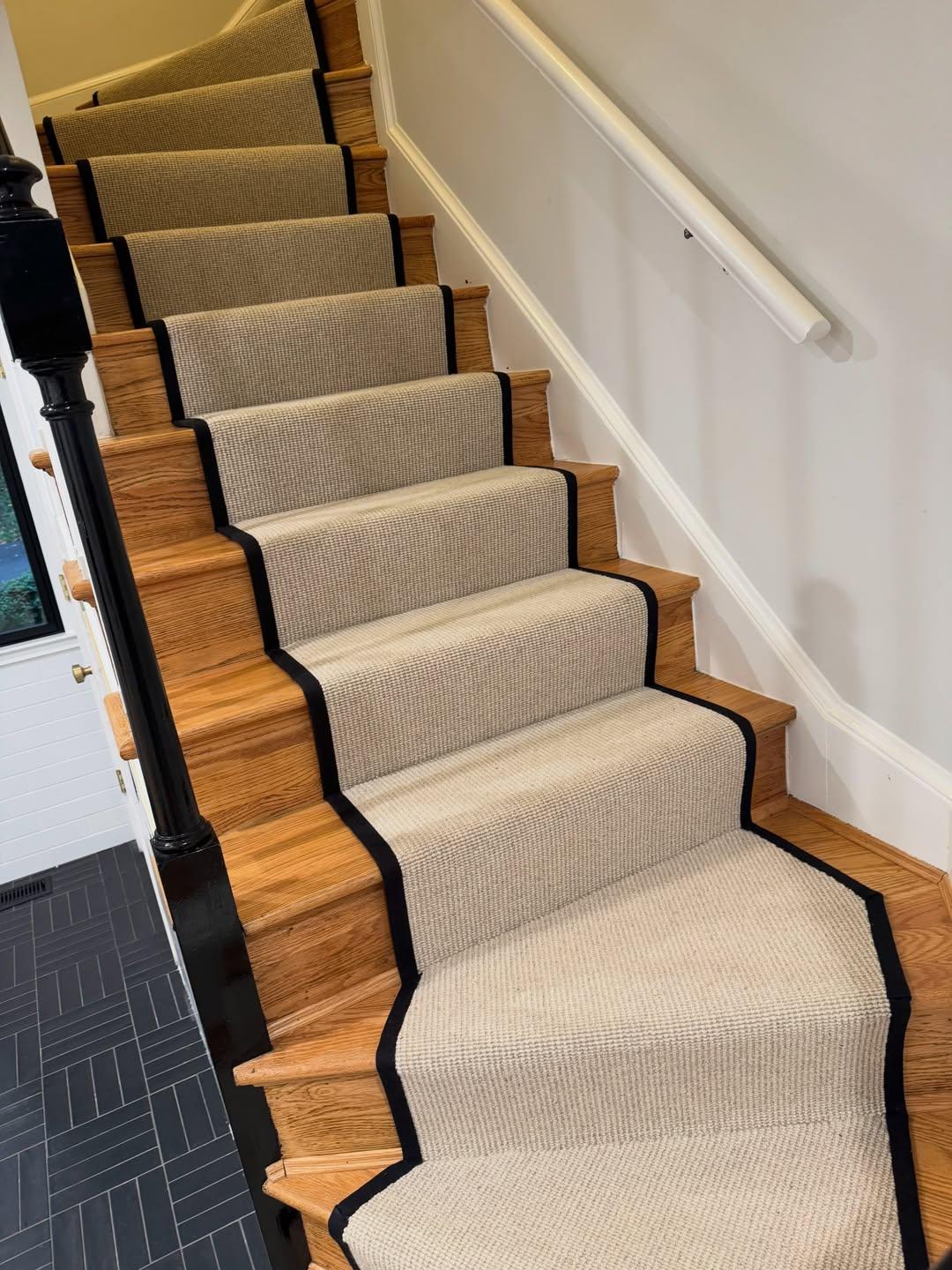 Cotton stair runner with a black bound border fitted around turning wood stairs